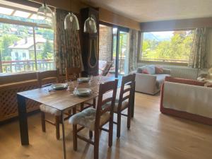 uma sala de jantar com uma mesa e cadeiras e um sofá em 2 Appartements près de Megève et terrain de tennis en été em Demi-Quartier