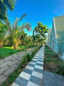 a walkway in front of a building with palm trees at Ruby Star Quỳnh Resort 