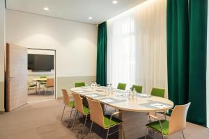 a conference room with a table and green chairs at IntercityHotel Lübeck in Lübeck