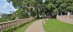 a walkway next to a fence with a field of grass at The Westin Mumbai Powai Lake in Mumbai