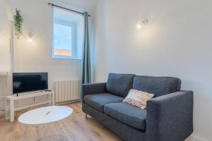 Una sala de estar con un sofá azul y un televisor. en 1 bedroom duplex apartment, with parking, en Tourcoing