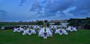 un grupo de mesas y sillas blancas en un campo en The Westin Mumbai Powai Lake en Bombay