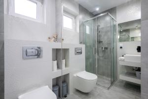 a white bathroom with a toilet and a shower at SunHouses in Darłowo