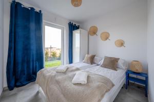 a bedroom with a bed with blue curtains and a window at SunHouses in Darłowo