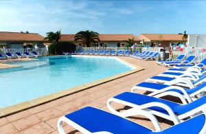 - une piscine avec des chaises longues bleues et blanches dans l'établissement Résidence Odalys Côté Canal, à Sallèles-dʼAude