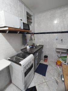 een kleine keuken met een fornuis en een wastafel bij Apartamento em condomínio fechado na Farolândia in Aracaju