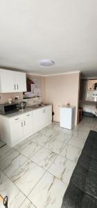 a kitchen with white cabinets and a tile floor at Cozy Batchelor Labiance in Cape Town