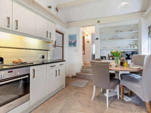 a kitchen with white cabinets and a table and chairs at 4 Bed in Torquay 94002 in Torquay