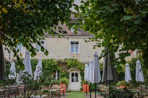 un groupe de parasols et de chaises devant un bâtiment dans l'établissement Logis Hostellerie des Clos et restaurant Bistrot des grands crus, à Chablis