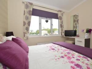 um quarto com uma cama grande com almofadas roxas e uma janela em 2 Bed in Tattershall Lakes 50360 em Tattershall