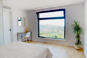 a bedroom with a large window and a bed at Heterotopia Villas in Chortáta