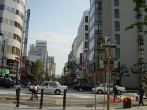 a busy city street with cars and people crossing the street at Mimatsuso Ryokan in Asahikawa