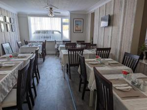uma sala de jantar com mesas e cadeiras num restaurante em The Ivernia hotel em Skegness