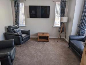 a living room with two chairs and a flat screen tv at The Ivernia hotel in Skegness