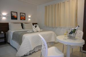 Un dormitorio con una cama y una mesa con una botella de vino en Pousada Galemares en Maragogi