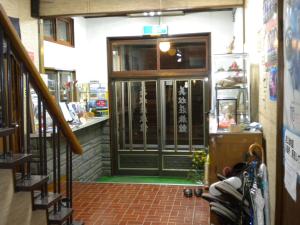 an entrance to a store with a green door at Mimatsuso Ryokan in Asahikawa