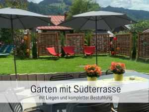 a table with two umbrellas in a yard at Ferienwohnungen Scholl - private Sauna oder Infrarotkabine in Bad Hindelang