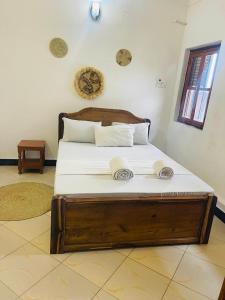 a bedroom with a wooden bed with white sheets at Digital nomad Cave- Zanzibar in Stone Town
