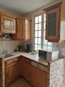 a kitchen with wooden cabinets and a sink and a microwave at maison entre terre et mer in Bonnebosq