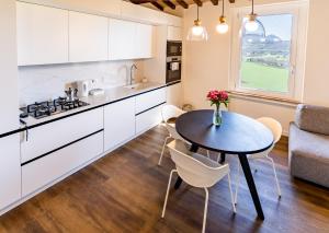 a kitchen with white cabinets and a table and a table and chairs at Incanto a Spello: Raffinato Appartamento per Due in Spello