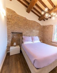 una camera con un grande letto e un muro di mattoni di Incanto a Spello: Raffinato Appartamento per Due a Spello