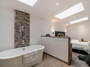 a bathroom with a bath tub and a bed at 2 Bed in Ticknall 93969 in Ticknall