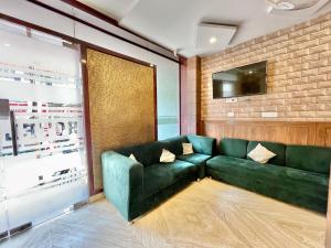 ein Wohnzimmer mit einem grünen Sofa und einem TV in der Unterkunft Hotel Janaki ! Varanasi ! fully-Air-Conditioned-hotel family-friendly-hotel, near-Kashi-Vishwanath-Temple and Ganga ghat in Varanasi