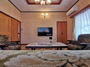 ein Wohnzimmer mit einem TV, einem Tisch und Stühlen in der Unterkunft Carpe Diem Kamaida in Ochi