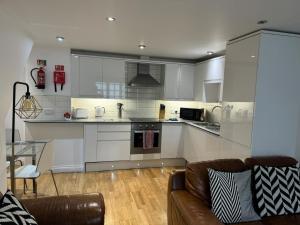 a kitchen with white cabinets and a couch in a living room at West Street Mews - Serviced Accommodation in Exeter