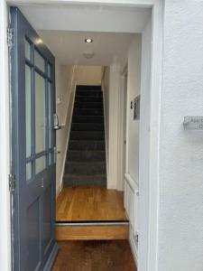 a hallway with a staircase with a blue door at West Street Mews - Serviced Accommodation in Exeter
