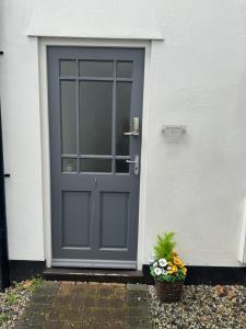 a gray door on a white house with a basket of flowers at West Street Mews - Serviced Accommodation in Exeter