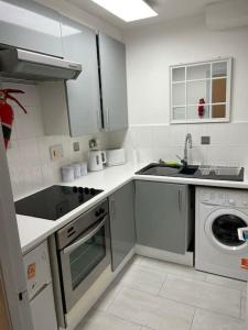 a white kitchen with a sink and a dishwasher at Casa de Canada Court in Glasgow