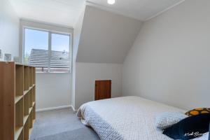 a white bedroom with a bed and a window at 5 bedroom modern house, private spacious backyard in Lower Hutt