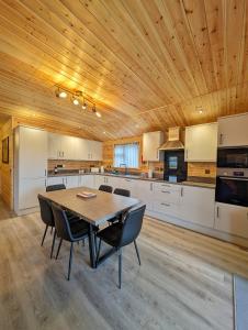 a kitchen with a wooden ceiling and a table and chairs at Ferry Lodge in Brundall