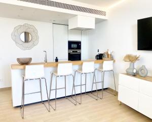 a kitchen with white cabinets and a counter with stools at Fantastic apartment in The Wave just steps from Carvajal Beach - Pool and free parking in Fuengirola
