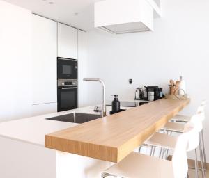 a kitchen with white cabinets and a wooden counter top at Fantastic apartment in The Wave just steps from Carvajal Beach - Pool and free parking in Fuengirola
