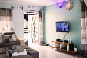 a living room with a couch and a tv on a wall at Stay in Bomang'ombe with Breakfast in Moshi