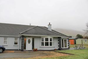 una casa blanca con un coche aparcado delante de ella en The Marshes - Large home, short drive to beach en Kells