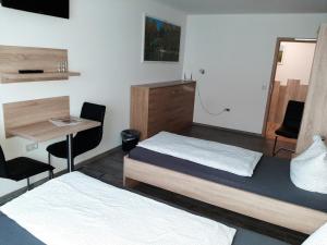 a room with two beds and a table and a desk at Haus Roseneck-Pension Am Stadtrand in Borchen