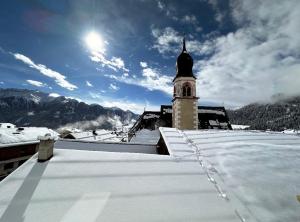 a snow covered roof of a building with a clock tower at Haus Pregenzer in Fiss