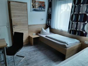 een kleine kamer met een bed en een stoel bij Pension 'Am Stadtrand' in Borchen