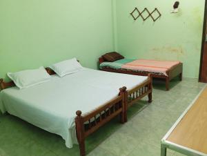 two twin beds in a room with a table at Nallur mylooran Arangam in Chiviyateru West