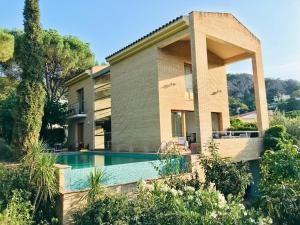 ein Haus mit Pool davor in der Unterkunft Architect Villa with Infinity Pool near Beach&Golf in Santa Cristina d'Aro