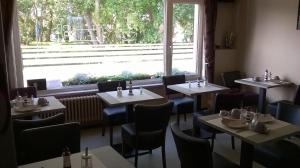 un restaurant avec des tables et des chaises et une grande fenêtre dans l'établissement Kokodor, au Coq