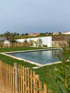 ein Pool in einem Garten neben einem Holzzaun in der Unterkunft Quinta Baltazar Casa particular in Vila Nova De Cacela