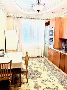 une cuisine avec une table et des chaises dans une pièce dans l'établissement 390 Очень теплая квартира с видом на Байтерек с 2 большими кроватями и 2 санузлами, à Astana