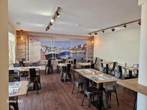 a restaurant with tables and chairs and a large window at Hotel Eisenhower (ex King Hôtel) in Port-en-Bessin-Huppain