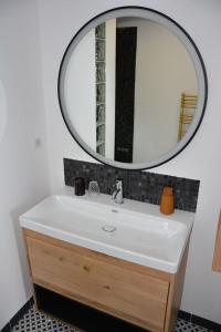 a bathroom with a white sink and a mirror at Le clos de la lande vallée in Bringal