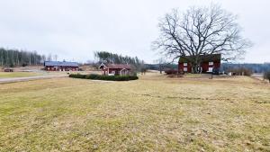a large field with a house and a tree at Large house, Baggetorp, close to swimming and fishing in Nykoping in Nyköping