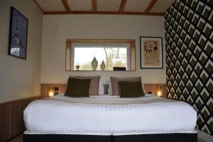 a bedroom with a large white bed with a window at Le clos de la lande vallée in Bringal